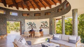 A spacious indoor area with a curved ceiling, a reception desk, two sofas, and a dining table.