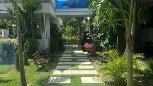 A pathway with artificial grass leading to a building with a blue sky view.