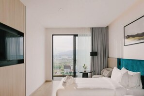 Une chambre d’hôtel moderne avec un grand lit, un bureau et une chaise. La fenêtre offre une vue sur la ville.
