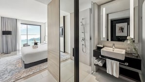 A modern hotel room with a large bed, a bathroom with a vanity, and a view of the sea. - December Hotel (Nha Trang)