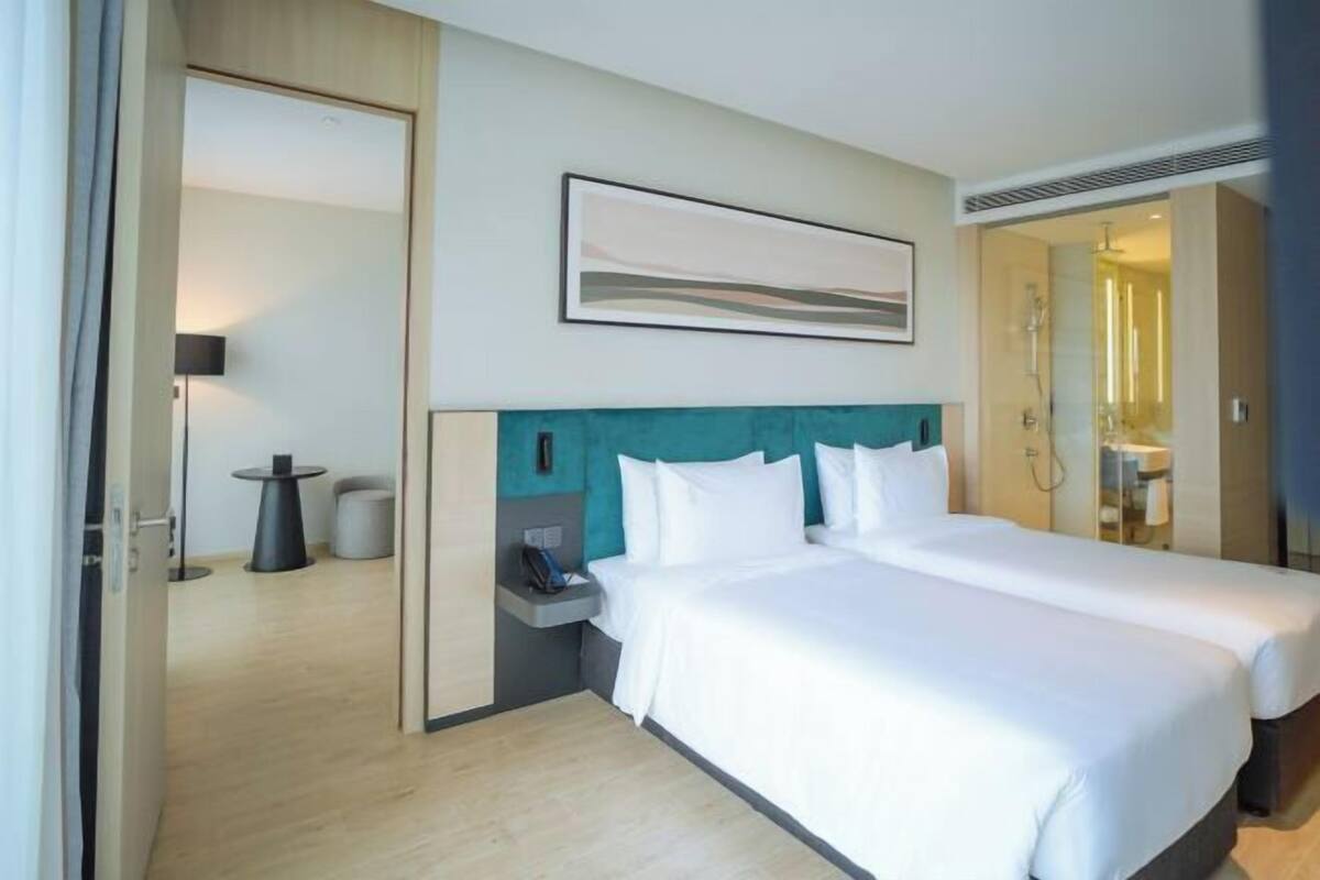 A hotel room with a bed, a nightstand, a lamp, and a framed picture on the wall.