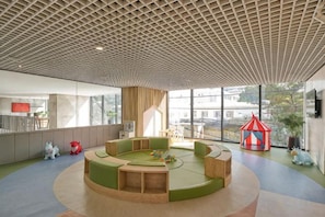 Een kinderspeelruimte met een rond zitgedeelte en een rode en witte speeltent.