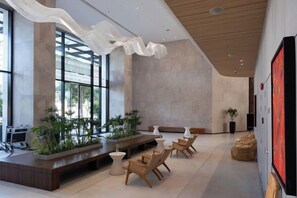 A modern interior with a reception desk, seating area, and large windows. - December Hotel (Nha Trang)