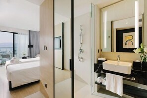 A modern hotel room with a large bed, a bathroom with a mirror, and a view of the city. - December Hotel (Nha Trang)