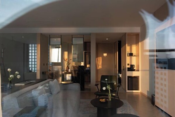 A modern hotel lobby with a sofa, a round table, and a chair. There is a glass partition and a small kitchenette area. - December Hotel (Nha Trang)