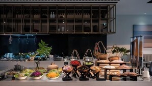 A buffet setup with various dishes and a large window in the background. - December Hotel (Nha Trang)