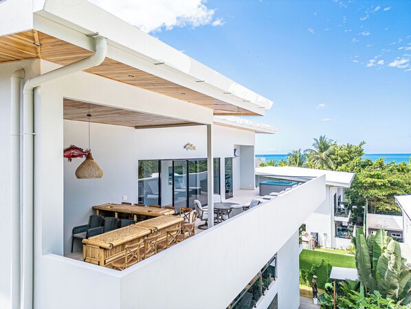 Un espacio exterior moderno para comer con muebles de mimbre y vista al océano.