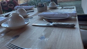 A dining table set with white plates, silverware, and a teapot, with a view of a brick building and trees outside. - Wethele Manor (Royal Leamington Spa)