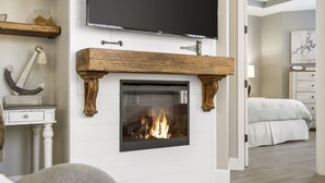 A modern living room with a fireplace, a television mounted above it, and a bed in the background. - Inviting Cliffs Condo, AMAZING views, next 2 SILVER DOLLAR CITY, Table Rock Lake (Branson)