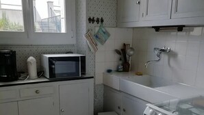 A compact kitchen with white cabinets, a microwave, a coffee maker, and a small sink.