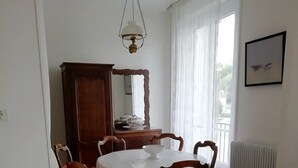 A dining area with a round table, wooden chairs, a wooden cabinet, and a radiator.
