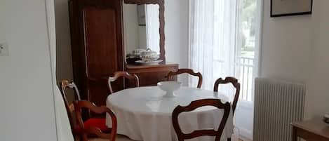 A dining area with a round table, wooden chairs, a wooden cabinet, and a radiator.