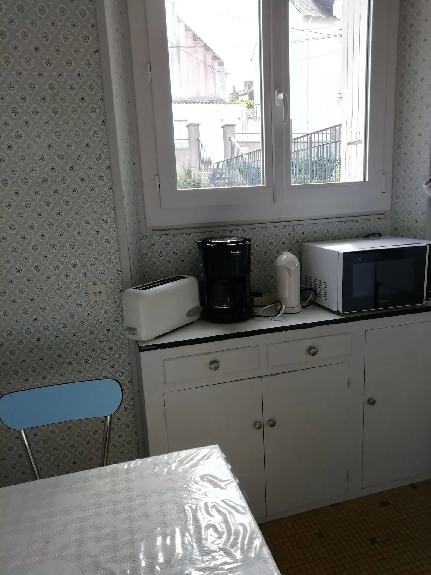 Una pequeña cocina con ventana, tostadora, cafetera y microondas en la encimera.