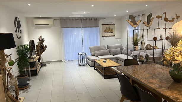 Ein modernes Wohnzimmer mit einem Ecksofa, einem Esstisch mit Stühlen und Dekorationselementen.