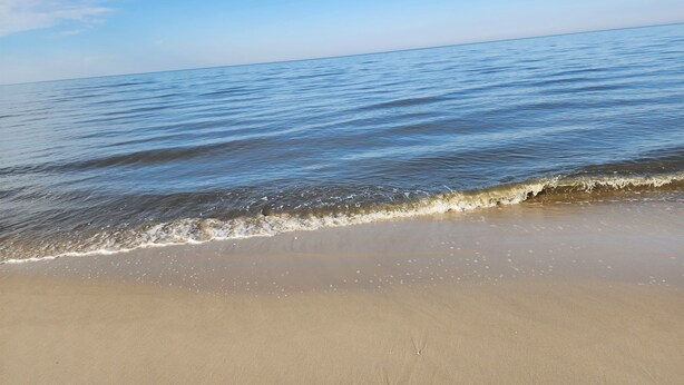 Een strand met helderblauw water en een zandstrand.