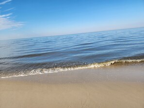 A beach with clear blue water and a sandy shore. - Pet-Friendly Cottage • 1 Block to Bay • EV • Chore-Free (Lower Township)