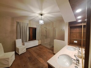 Une salle de bain spacieuse avec un grand miroir, deux lavabos et un espace douche.