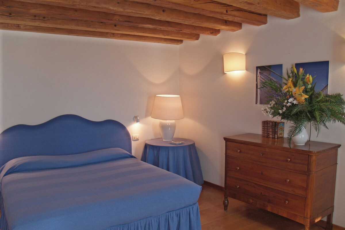 Une chambre à coucher comprenant un lit, une commode, une lampe et un luminaire fixé au mur.