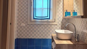 Un baño con ventana, lavamanos y azulejos azules.