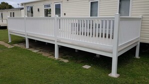 Una casa mobile con un patio bianco e un piccolo portico.