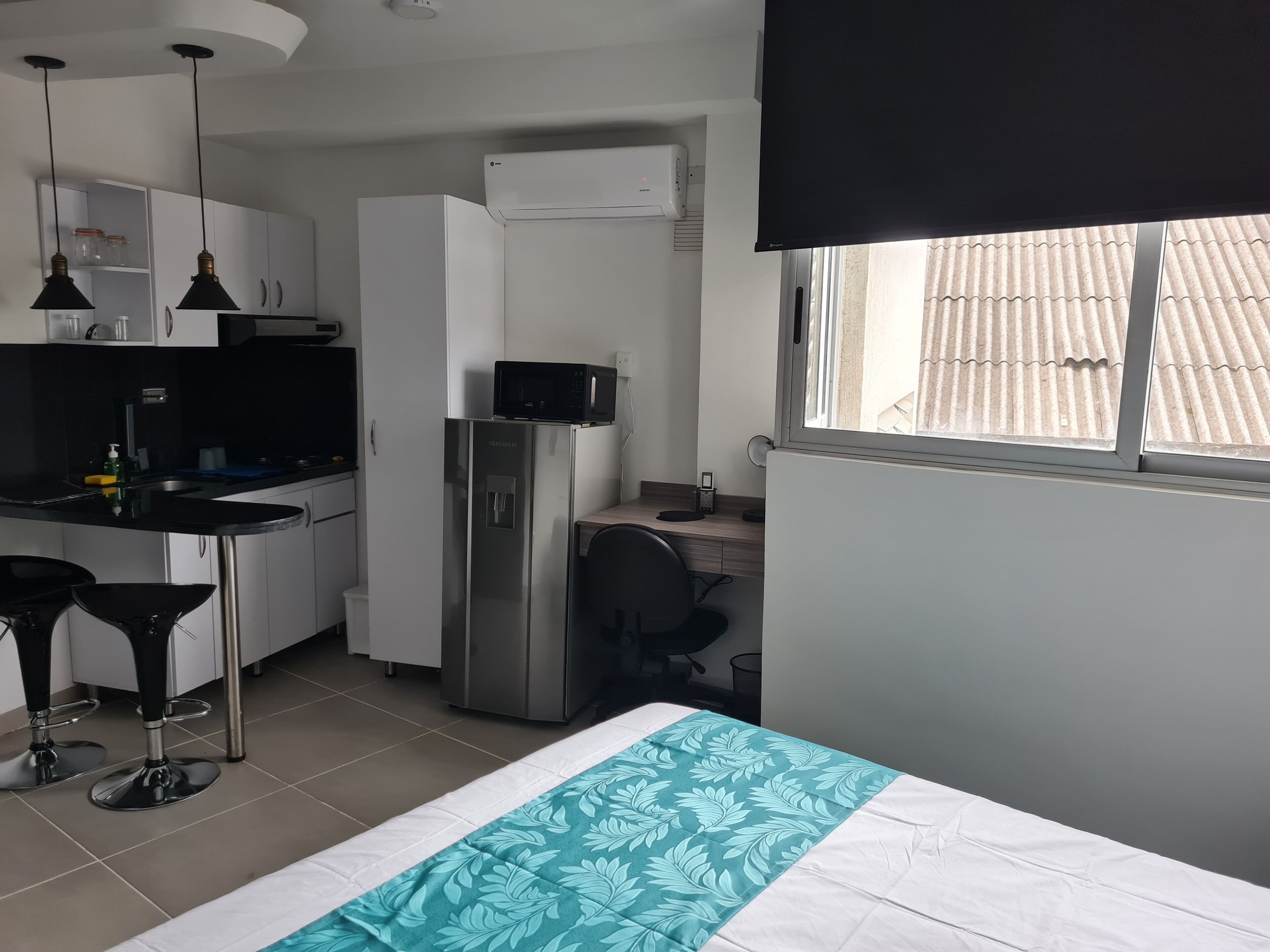 Habitació senzilla amb llit, petita cuina i finestra.