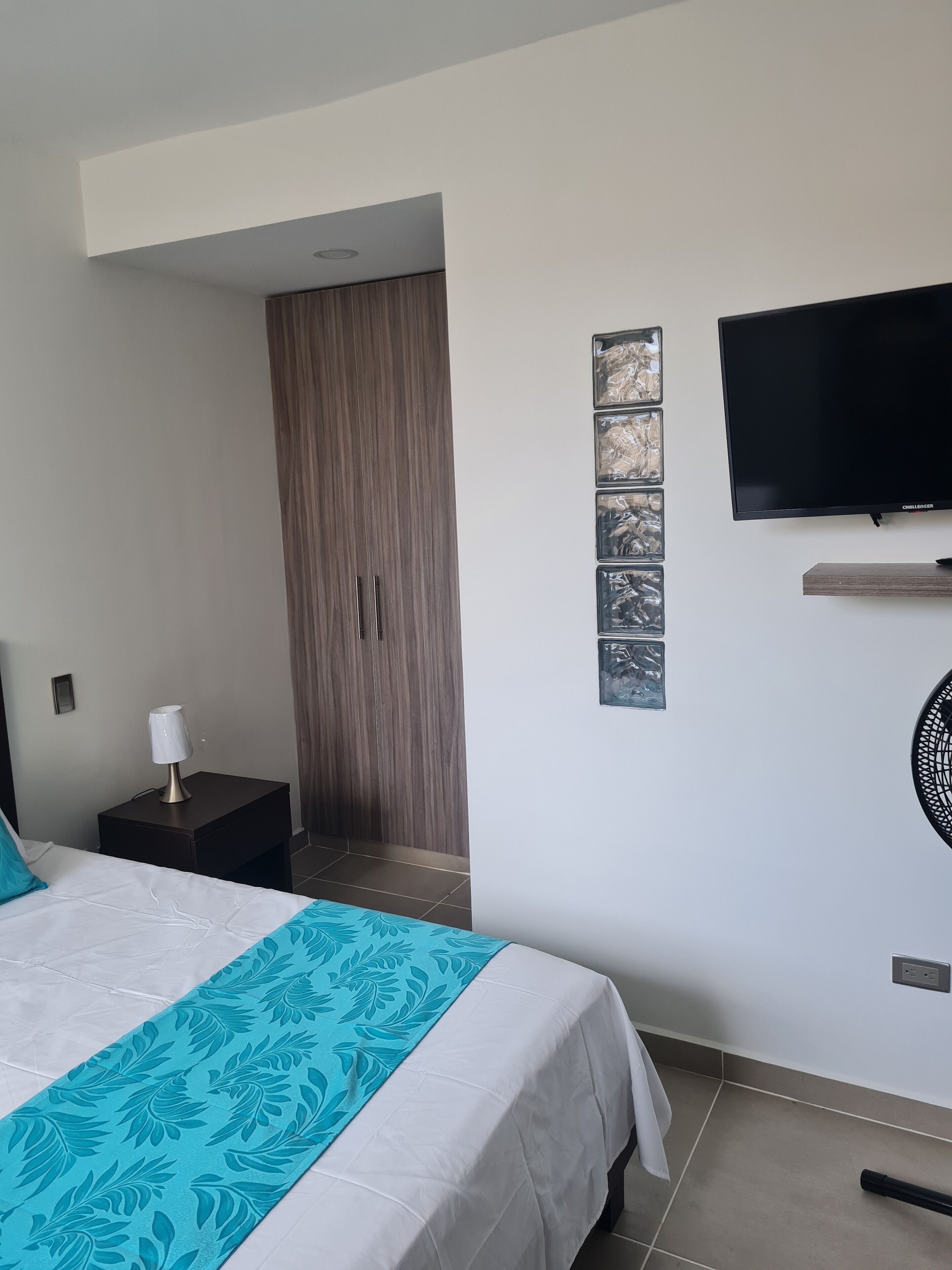 Une chambre d’hôtel comprenant un lit, une table de chevet, une télévision et une armoire.