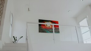 Un intérieur moderne avec un escalier, un tableau au mur et une plante.