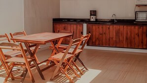 Une cuisine de taille réduite, avec une table et des chaises en bois, un plan de travail noir et un meuble en bois.