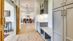 A modern kitchen with grey cabinets, a dining area with a wooden table and chairs, and a hallway with wooden flooring. - Large Group Getaway in Georgetown w/ Private Pool! (Georgetown)