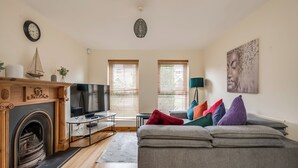 A living room with a fireplace, television, sofa, and windows. - Stylish & spacious entire 3+1BR house in Lisburn(near Belfast)with parking  (Lisburn)