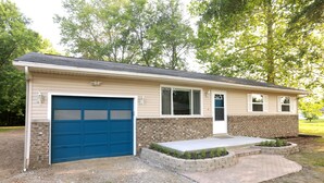 A single-story house with a blue garage door, a brick exterior, and a front porch with a small garden. - Charming 3 bedroom retreat (Herrin)