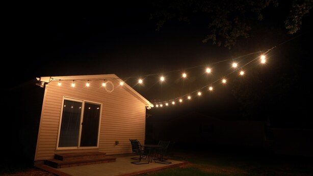 A small house with a covered patio, string lights, and a sliding glass door. - Charming 3 bedroom retreat (Herrin)