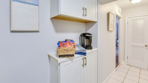 Ein Flur mit einem weißen Schrank, einem gerahmten Bild, einer Snack-Korb und einer Kaffeemaschine.