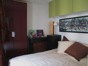 Relax in a stylish room with a comfortable bed, desk, and artwork.