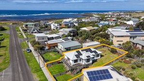 An aerial view of a coastal residential area with houses, a road, and a beach. - The Lost Lobster - Beach Shack (Port Fairy)