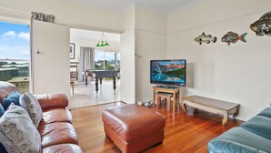 A living room with a pool table, leather sofas, a television, and decorative fish on the wall. - The Lost Lobster - Beach Shack (Port Fairy)