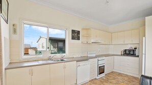 A modern kitchen with white cabinets, a built-in oven, a microwave, and a dishwasher. - The Lost Lobster - Beach Shack (Port Fairy)