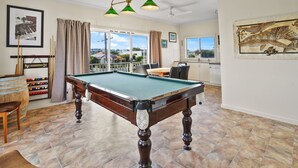 A pool table in a room with a view of the outdoors, a dining area, and a kitchen. - The Lost Lobster - Beach Shack (Port Fairy)