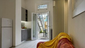 Um espaço compacto com cozinha compacta, cama com cobertor, escada e vista para o exterior.