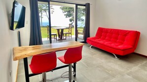 Une pièce moderne comprenant un coin repas, un canapé rouge et un téléviseur fixé au mur.