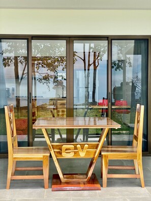 A dining area with a wooden table and chairs, large glass windows, and a view of the outdoors.