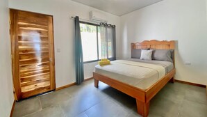 Een slaapkamer met een houten bed, een raam met gordijnen en een plafondventilator.