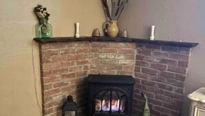 A corner fireplace with a brick design, a mantel with decorative items, and a rug on the floor. - Charming cozy cottage downtown Petaluma (Petaluma)