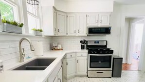 Uma cozinha moderna com armários brancos, fogão de aço inoxidável e micro-ondas.