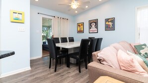 Un espace repas comprenant une table et des chaises, un ventilateur de plafond et des œuvres d’art murales.