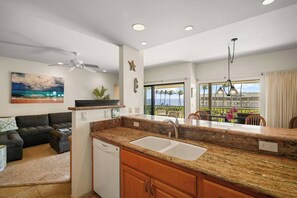 Una cocina moderna con encimera de granito, pileta integrada y ventilador de techo.
