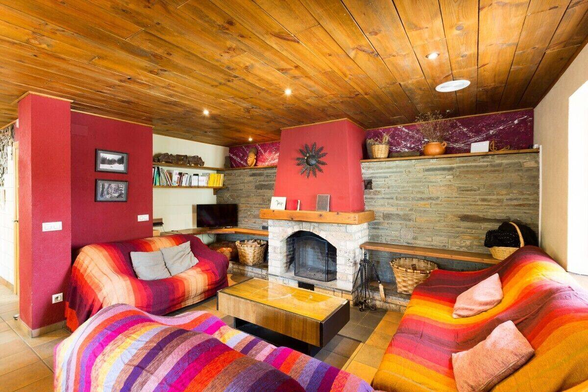 A cozy living room with a fireplace, wooden ceiling, and colorful striped sofas.