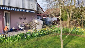 Una casa con jardín, narcisos y un árbol.