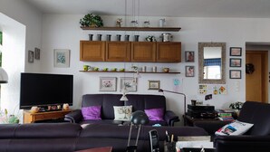 Una sala de estar con un sofá, una televisión y una estantería.