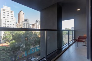 A modern apartment with a balcony, large windows, and a view of the cityscape.